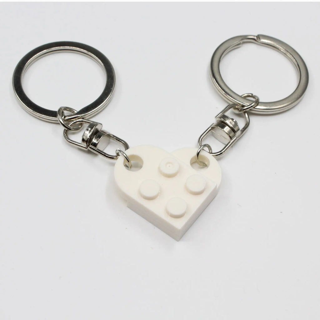 Couple heart keychains held in hand close‑up